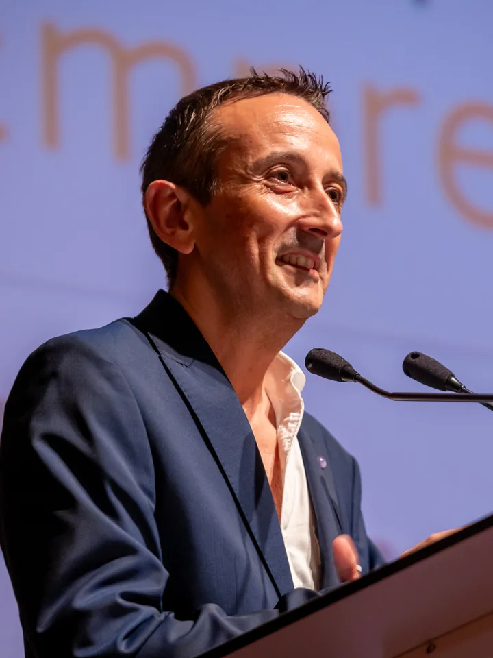 Josep Maria Raya sonriendo durante una intervención en un acto, con americana azul